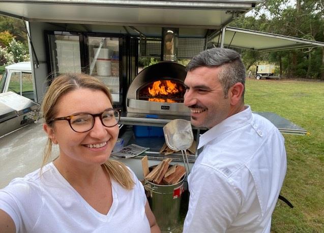 A person and person standing in front of a fire pit Description automatically generated with low confidence